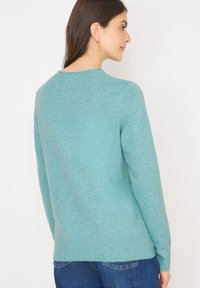 Turquoise trui met een gestructureerde afwerking, voorzien van een ronde hals en ribbelboord. Lange mouwen en een relaxte pasvorm maken het ontwerp compleet.