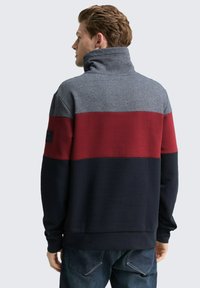 Fleece sweatshirt met een kleurafgebakend ontwerp in grijs, bordeauxrood en marineblauw. Hoge kraag en ribgebreide manchetten, met een opvallend merkdetail.
