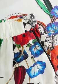 Bloemmotief stof met blauwe, rode en zwarte elementen, voorzien van een geplooid tailleontwerp. Gladde textuur met decoratieve accenten.