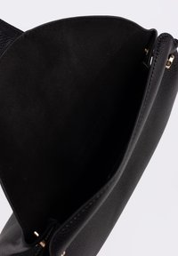 Borsa in pelle nera con esterno strutturato. Interno in morbido tessuto nero. Dotata di dettagli in oro e chiusura magnetica semplice.