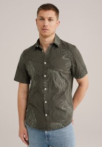 Camisa de botones de manga corta en tela verde oscuro con estampado blanco de hojas tropicales, con cuello clásico y dobladillo recto.