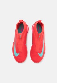 Piros slip-on sportcipők textúrált felsőrésszel, kék Nike logóval és belső zöldes-kék béléssel a kényelem érdekében.