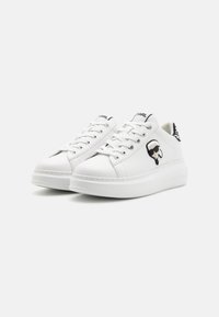 Hvite sneakers med en glat overflade, rund tå, snøredesign og et tegneserie-logo på siden. Tykk hvid såle med stikninger.