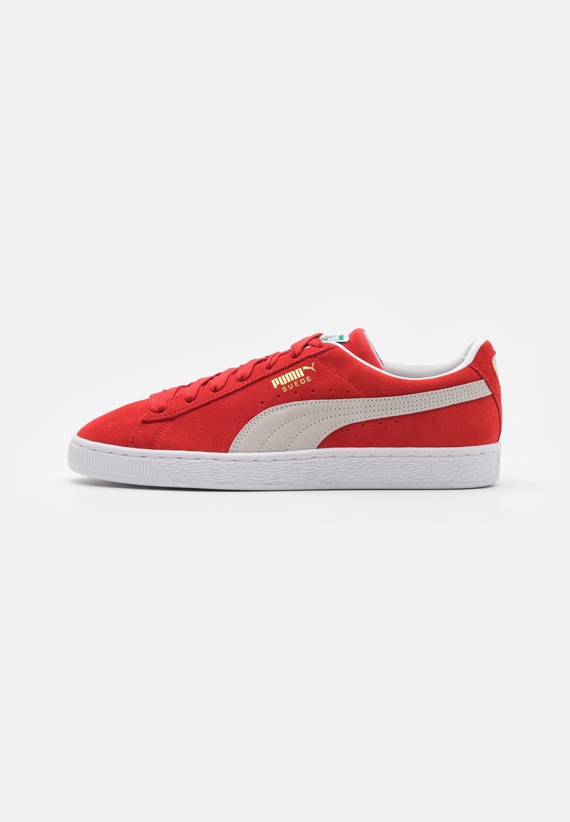 Baskets rouges en daim Puma avec bande blanche, semelle blanche et logo Puma doré sur le côté, vues de profil sur un fond blanc.