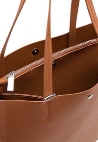 Borsa a tracolla in pelle marrone con texture liscia, cerniera argento e due manici. All'interno presenta un rivestimento beige con dettagli funzionali.