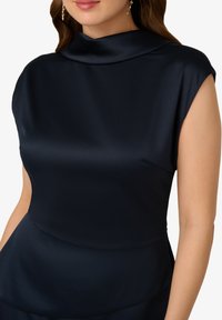 Námořnická saténová blůza s vysokým cowl krkem, krátkými rukávy a hladkým, lesklým povrchem. Nabízí přiléhavý siluetu a minimalistický design.