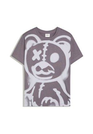 Grå t-shirt med korte ærmer med hvid graffiti-stil tegning af en teddybjørn med et overskrevet øje og syet mund.