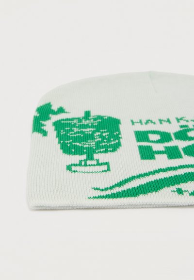 Άσπρο πλεκτό σκουφάκι με πράσινα σχέδια που περιλαμβάνουν ένα τρόπαιο, ένα πουλί και μερικό κείμενο στο μπροστινό μέρος.