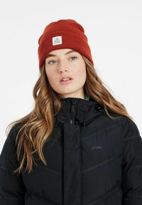Sort puff jakke med lynlås, der har hætte og diskrete mønstrede accenter. Orange strikket hue med et logo-patch foran.
