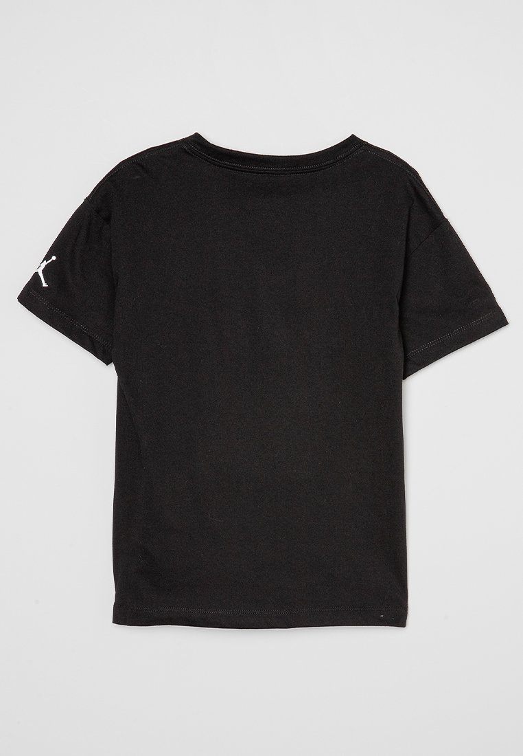 Camiseta de algodón negra con mangas cortas, cuello redondo y un logo blanco en la manga izquierda. Textura suave, diseño casual.