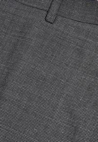Textureret stof i mørkegrå med et subtilt mønster. Har et lige design og en talje, der giver en struktureret pasform.
