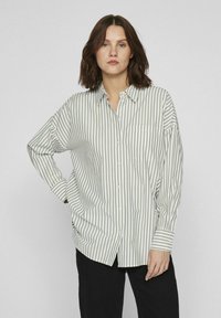 Camisa de botones con rayas verticales verdes y blancas, corte amplio, mangas largas, cuello y un bolsillo en el pecho.
