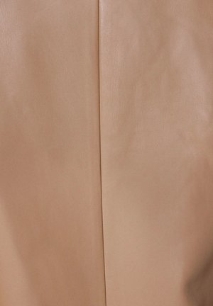 Beige läder tyg med en slät textur, med en vertikal söm som löper ner i mitten. Diskret glänsande yta framhäver dess kvalitet.