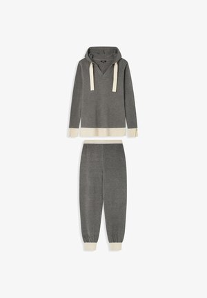 Sweat à capuche gris avec des accents beiges et des cordons, associé à un pantalon de jogging fuselé assorti. Tissu doux avec des poignets et un ourlet côtelés.