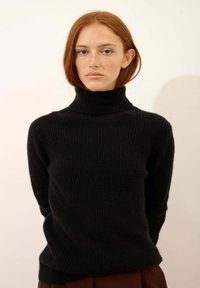 Czarny, prążkowany sweter z golfem wykonany z miękkiego materiału, z długimi rękawami i luźnym krojem. Prosty design bez dodatkowych akcentów.