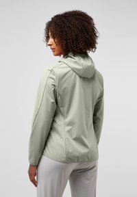 Veste vert clair en tissu lisse avec capuche, coupe cintrée et manches longues. Présente une construction simple sans motifs supplémentaires.