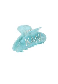 Aqua blue plastic hair clip with a butterfly shape; features rhinestones spelling “KAWI” and toothed grip for secure hold.