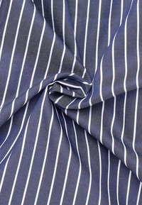 Tessuto navy con sottili strisce bianche, dalla superficie liscia e con un design attorcigliato, che mette in risalto un classico motivo a righe.