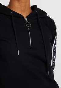 Černá mikina s kapucí na zip, s šňůrkou a bílými logy na rukávech. Měkká textura a uvolněný střih.