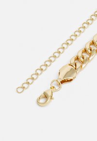 Zlata zapestnica iz debelih členov, ki vsebuje sponko na ježka in manjšo podaljšano verigo za prilagodljivo dolžino. Gladka kovinska površina.