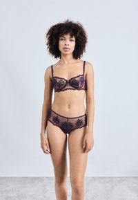 Lace lingerie set in deep purple featuring a sheer, floral-embroidered bra and matching panties with scalloped edges.