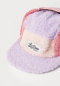 Gorro de forro polar en púrpura, rosa y crema con visera plana; presenta un diseño texturizado y una etiqueta con el logo que dice "Lii'Boo Copenhagen."