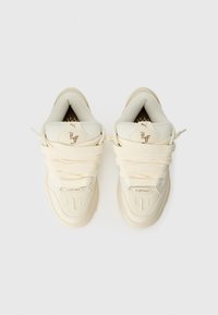 Kremfargede sneakers med teksturert lær, tykke lisser, polstret krage, preget logo og kontrasterende detaljer på sålen og tungen.