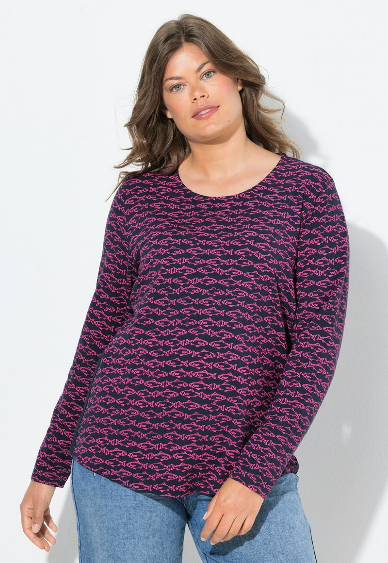 Pitkähihainen t-paita tummansinistä puuvillaa, jossa on vaaleanpunaisia kala-kuvioita, pyöreä pääntie ja rento malli, yhdistettynä vaaleansinisiin farkkuihin.