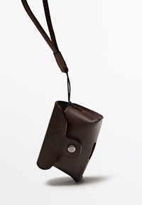 Borsetta in pelle marrone con una texture liscia, design curvo, chiusura a pressione in argento e un laccetto per l'attacco.