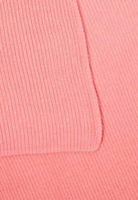 Tessuto rosa texturizzato con motivo a righe, che mette in mostra un aspetto morbido e accogliente. Il materiale sembra lavorato a maglia con tonalità leggermente variabili.