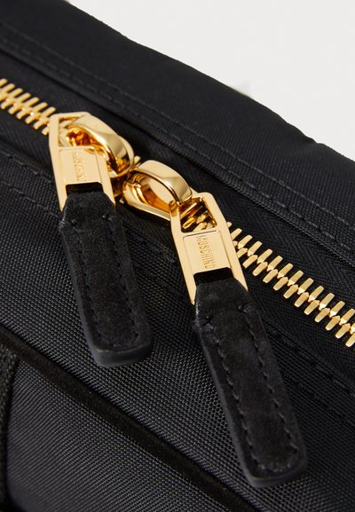 Geantă din material textil negru, cu un fermoar auriu prevăzut cu două mânere metalice mari, finisată cu accente din suede negru și cusături detaliate.