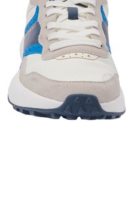 Eesvaade beežidest, valgetest ja sinistest sneakeritest, millel on valged paelad, sametist ja perforeritud nahast ülemine osa ning tekstureeritud tume sinine tald.