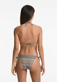Zöld nyakba akasztható, tarka kötött anyagból készült bikini szett hullámmintákkal, oldalán kötőkkel a bugyin.