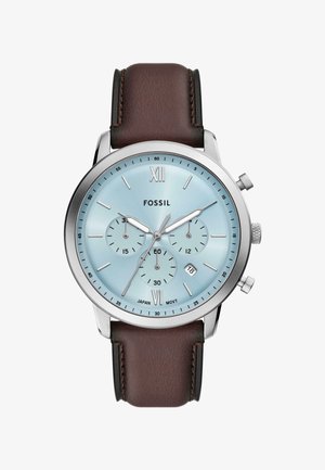 Chronograph watch with light blue dial, silver-tone case, brown leather strap, and date display; features three subdials and Roman numerals.