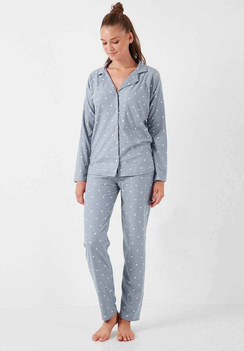 Ensemble de pyjama gris en tissu doux comprenant une chemise à boutons à pois blancs et un pantalon assorti. Manches longues et coupe décontractée.