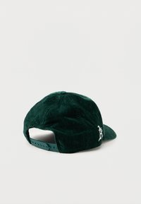 Zelená sametová čiapka s ohnutým okrajom a nastaviteľným plastovým remienkom. Na boku sa nachádza biele vyšívané logo. Hladký povrch.