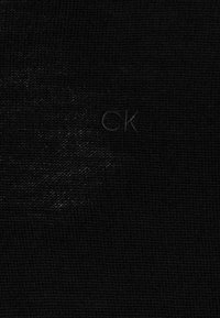 Tessuto nero con una trama testurizzata, caratterizzato da un logo sottile in una tonalità più chiara. Un design semplice e sobrio senza motivi visibili.