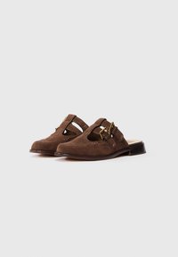 Hnedé semišové slip-on topánky s otvoreným dizajnom, s akcentami zlatého hardvéru a nízkym plochým dreveným podpätkom. Štruktúrovaný povrch so švovými detailmi.