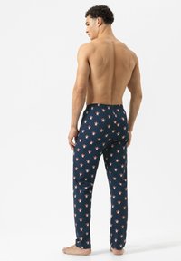 Navyblauwe slaapbroek met een bloemenpatroon in rood en wit. Gemaakt van zacht materiaal, met een elastische tailleband en een recht model.