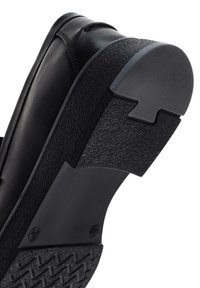 Zapato de cuero negro con suela de goma texturizada. El tacón cuenta con un diseño moldeado y un panel mate en contraste para mejorar el agarre.