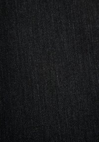 Zwarte denimstof met een gladde textuur, waarin een subtiele taftweefsel en lichte kleurvariatie doorheen zichtbaar zijn. Geen zichtbare patronen of accenten.