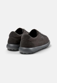 Schwarze Sneakers mit einem glatten Lederoberteil und Akzenten aus Wildleder, einer abgerundeten Silhouette und einer strukturierten Gummisohle. Die Rückansicht zeigt die Schnürdetails.