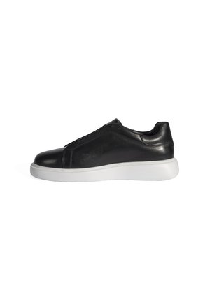 Baskets noires en cuir à enfiler avec un dessus lisse, un orteil arrondi et une semelle en caoutchouc blanche, offrant un design minimaliste.