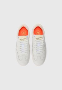 Ein Paar weiße Leder-Sneaker mit weißen Schnürsenkeln und helloranchen Innensohlen, mit Scotch & Soda-Branding auf den Zungen und Innensohlen.