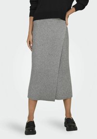 Falda lápiz gris de canalé con diseño envolvente, de longitud a la rodilla, combinada con zapatos negros de deslizamiento. La tela es texturizada y suave.