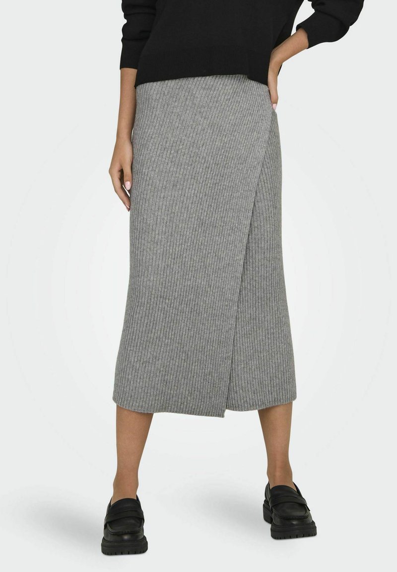 Falda lápiz gris de canalé con diseño envolvente, de longitud a la rodilla, combinada con zapatos negros de deslizamiento. La tela es texturizada y suave.