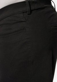 Černé džíny z hladkého materiálu s středním pasem, bočními kapsami a jemnými prošívacími detaily na švech.