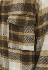 Flanelirana košulja s smešnim i bež kariranim uzorkom, dugmad-otvoreni dizajn, jedan džep na grudima, mekan tekstur i topla tkanina.