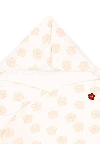 Wrap blanc doux pour bébé avec des imprimés floraux rose pâle, des boutons-pression et un petit détail brodé d'une fleur rouge sur le devant.