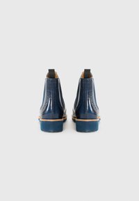 Bottines en cuir bleu marine avec une finition lisse, des détails en brogue décoratifs, des tirettes et un talon en caoutchouc bleu.